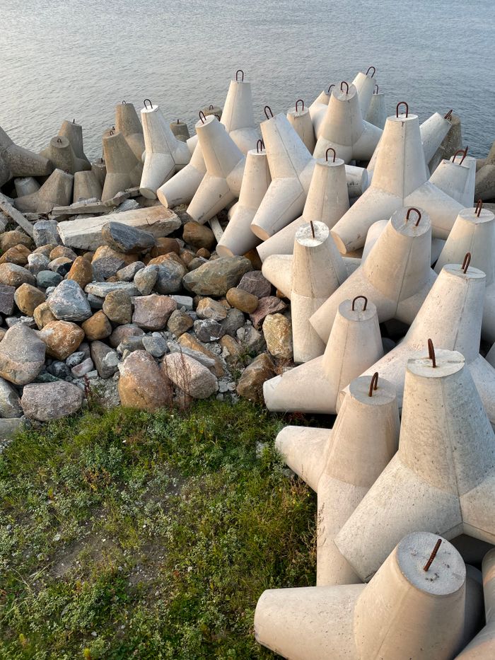 Concrete breakwater and stones on Tallinn's shore at sunset, Estonia.