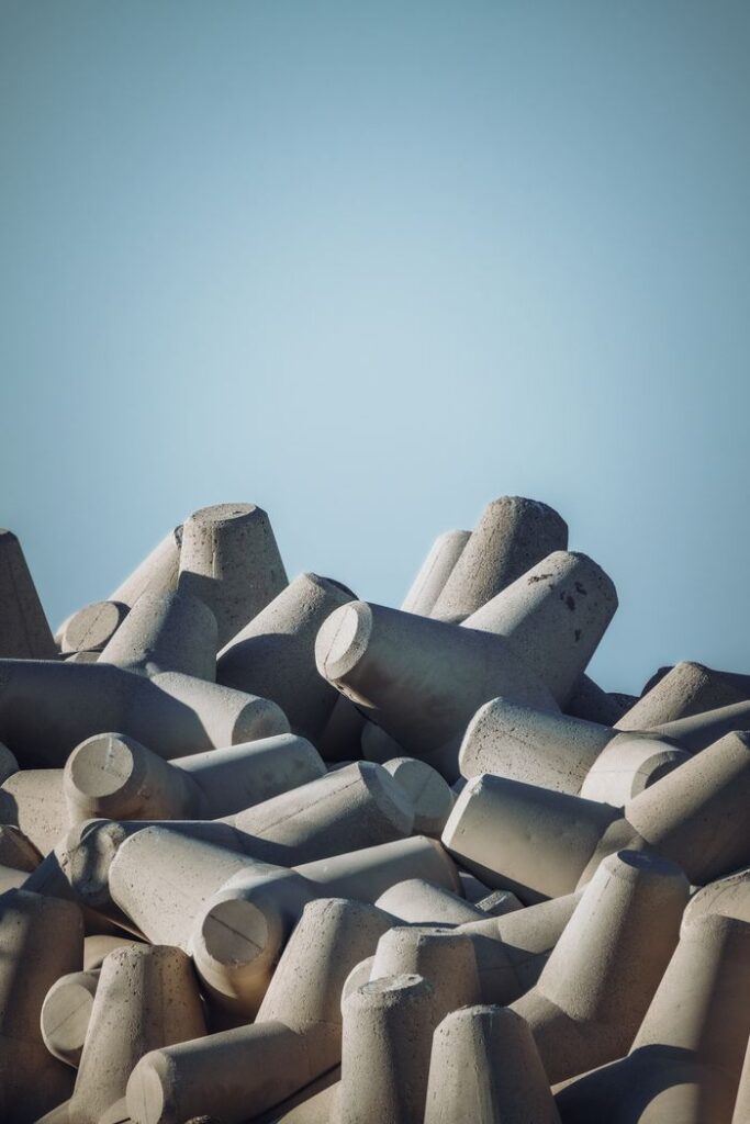 Pile of grey concrete tetrapods stacked outdoors under a clear blue sky.
